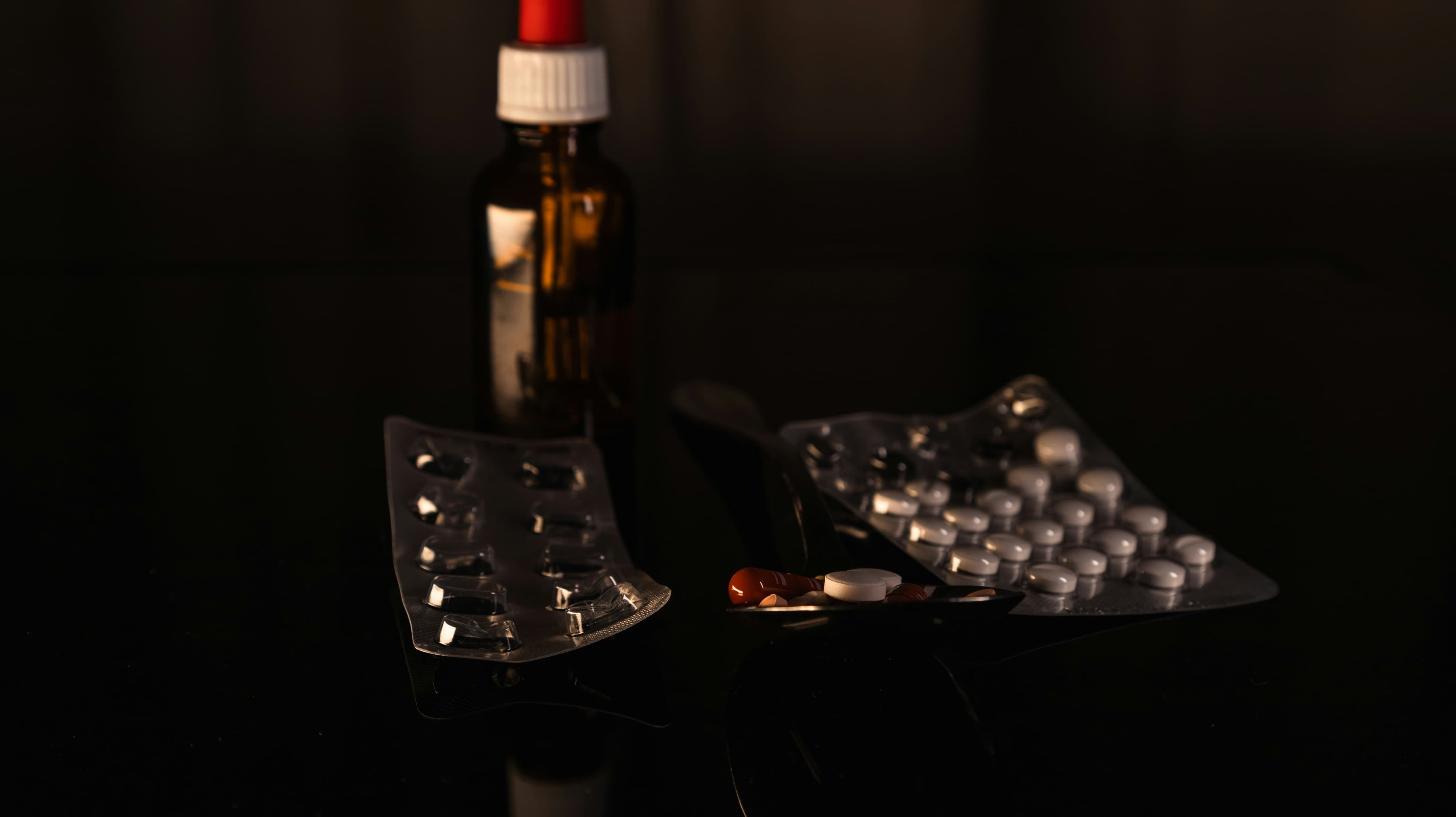 Supplement bottle and tablets arranged in dark light